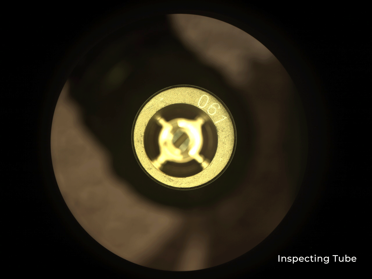 Cachecam looks down at the circular opening of a Perseverance witness tube, with metallic fittings around its center.