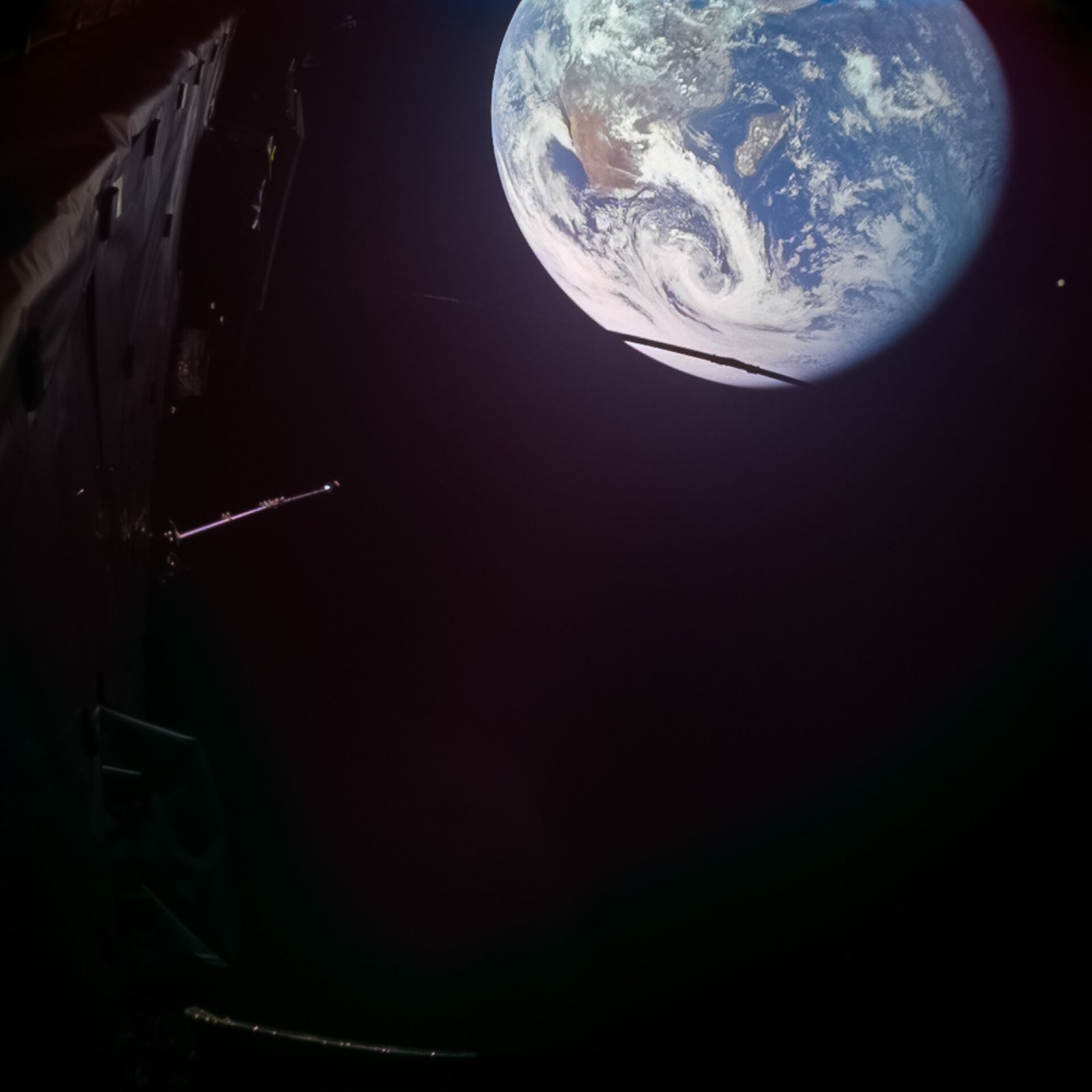 Earth appears above spacecraft structure in a Juice monitoring-camera image, with Africa and Madagascar visible and the Moon a small dot at upper right.
