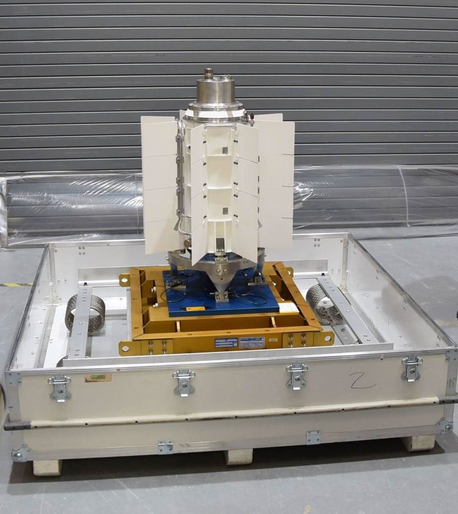 Mars 2020 MMRTG hardware with pale radiator fins stands on a metal support in a laboratory photograph.
