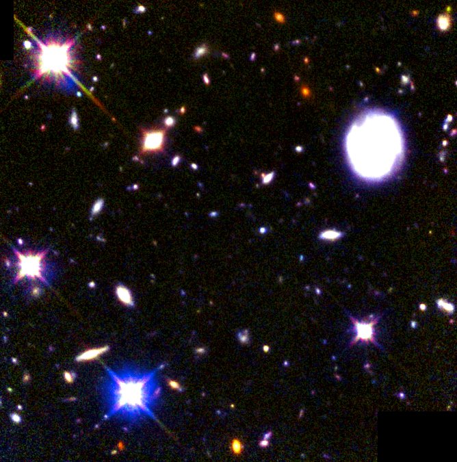 White, blue and orange galaxies and bright foreground stars in a Hubble Deep Field South composite.